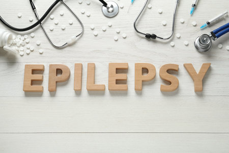Word Epilepsy made of wooden letters, stethoscopes, pills and syringes on white table, flat layの写真素材