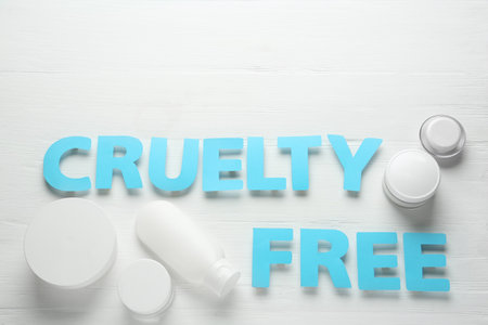 Flat lay composition with words Cruelty Free and different cosmetic products not tested on animals against white wooden backgroundの写真素材