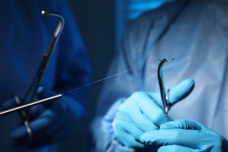 Professional surgeons with forceps and suture thread on blurred background, closeup. medical equipmentの写真素材