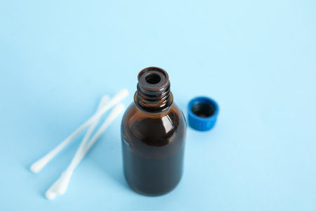 Bottle of medical iodine and cotton buds on light blue background, closeupの写真素材