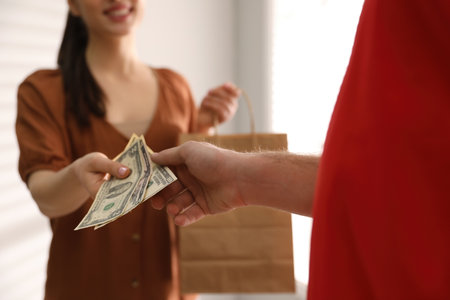 Woman giving tips to deliveryman indoors, closeupの写真素材