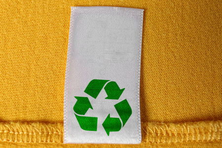 Clothing label with recycling symbol on yellow sweater, closeup viewの写真素材