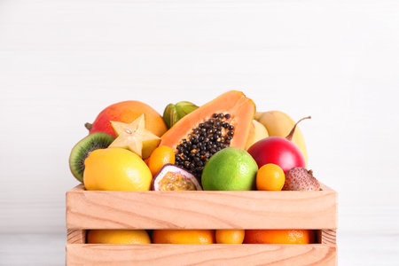 Different tropical fruits in wooden box on white background, closeupの写真素材