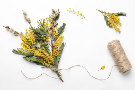 Beautiful mimosa bouquet and twine on white background, flat layの写真素材