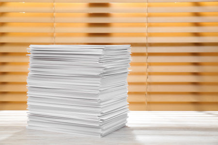 Stack of paper sheets on white wooden table. Space for textの写真素材