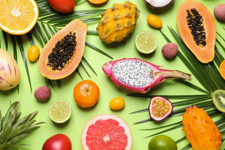 Different exotic fruits and palm leaves on green background, flat layの写真素材