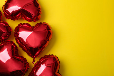 Red heart shaped balloons on yellow background, space for text. Valentine's Day celebrationの写真素材