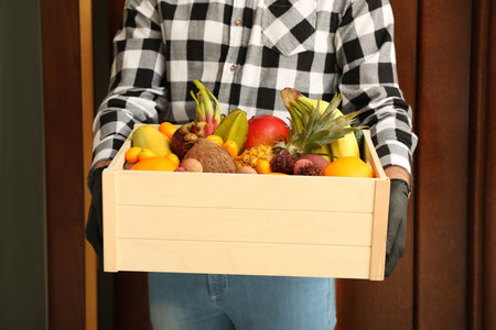 Courier holding crate with assortment of exotic fruits outdoors, closeupの写真素材