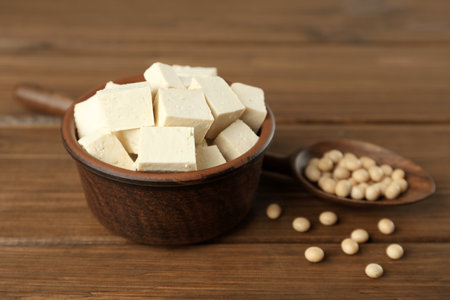 Pieces of delicious tofu in bowl and soy on wooden tableの写真素材