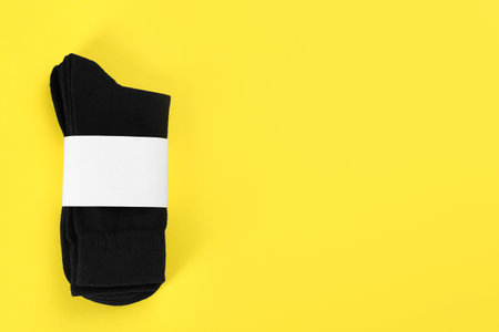 Pair of black cotton socks on yellow background, top view. Space for textの写真素材