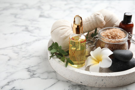 Beautiful spa composition with essential oil and plumeria flower on white marble table, space for textの写真素材