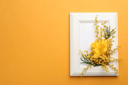 Beautiful floral composition with mimosa flowers and frame on orange background, top view. Space for textの写真素材