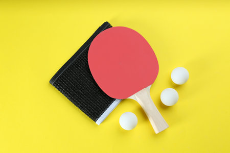 Table tennis racket, net and balls on yellow background, flat layの写真素材