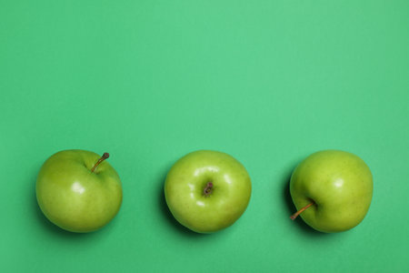Apples on green background, flat lay. Space for textの写真素材