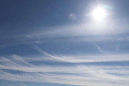 Bright sun and fluffy white clouds in blue skyの写真素材
