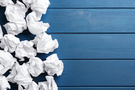 Crumpled sheets of paper on blue wooden background, flat lay. Space for textの写真素材