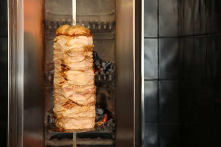 Vertical rotisserie with roasted meat in restaurant kitchen. Space for textの写真素材