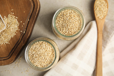 Jars and spoon with white quinoa on light gray table, flat layの写真素材