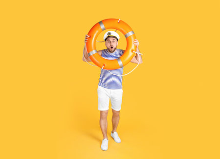 Emotional sailor with ring buoy on yellow backgroundの写真素材