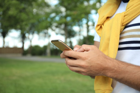 Man with smartphone in park on summer day, closeupの写真素材