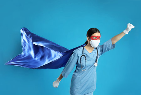 Doctor dressed as superhero posing on light blue background.の写真素材