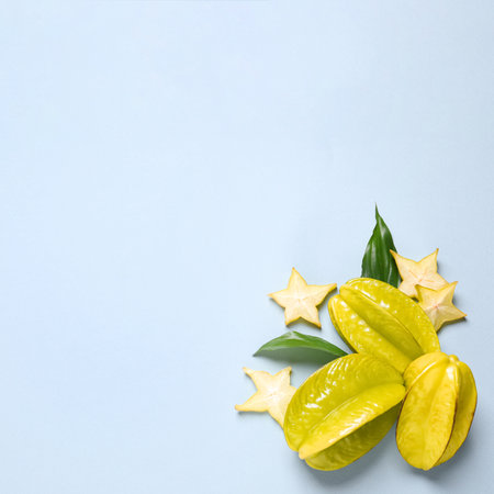Delicious carambola fruits on light blue background, flat lay. Space for textの写真素材