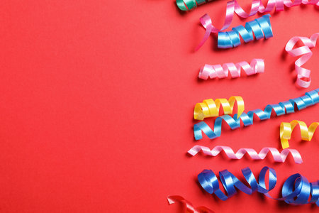Colorful serpentine streamers on red background, flat lay. Space for textの写真素材