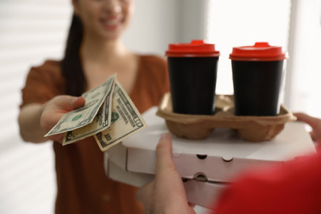 Woman giving tips to deliveryman indoors, closeupの写真素材