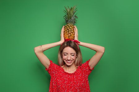 Young woman with fresh pineapple on green background. Exotic fruitの写真素材