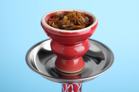 Modern hookah with tobacco on light blue background, closeup