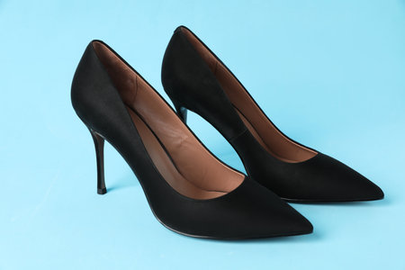 Pair of elegant black high heel shoes on light blue backgroundの写真素材