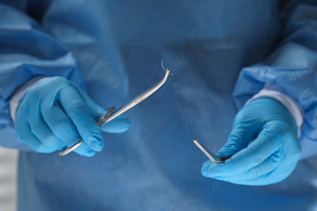 Professional surgeon holding forceps with suture thread, closeup. medical equipmentの写真素材