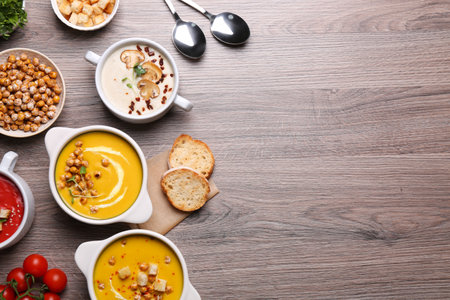 Different tasty cream soups and bread on wooden table, flat lay. Space for textの写真素材
