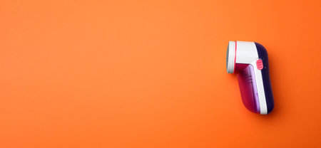 Modern fabric shaver on orange background, top view. Space for textの写真素材
