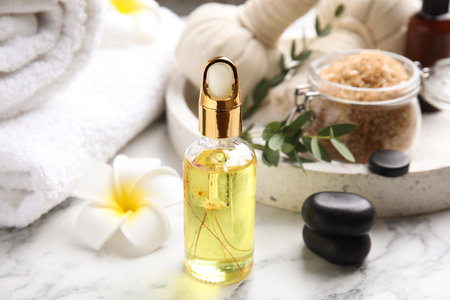 Beautiful spa composition with essential oil and plumeria flower on white marble tableの写真素材