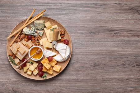 Cheese plate with honey, grapes and nuts on wooden table, top view. Space for textの写真素材
