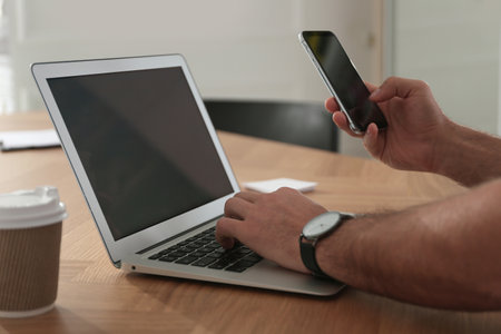 Freelancer working with laptop and smartphone at table indoors, closeupの写真素材