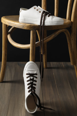 Pair of stylish shoes with brown laces and chair indoorsの写真素材