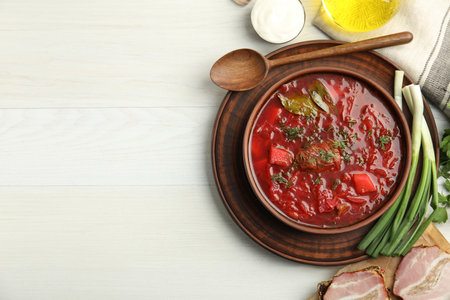 Stylish brown clay bowl with Ukrainian borsch served on white wooden table, flat lay. Space for textの写真素材