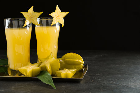 Delicious carambola juice in glasses on black table. Space for textの写真素材