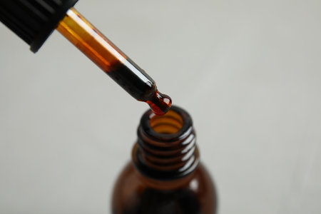 Dripping medical iodine from pipette into glass bottle on gray background, closeupの写真素材