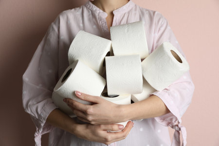 Woman with heap of toilet paper rolls on pink background, closeupの写真素材