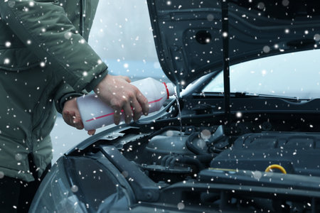 Man filling car radiator with antifreeze outdoors, closeupの写真素材