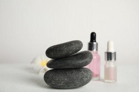 Stack of gray spa stones, oils and flower on white tableの写真素材