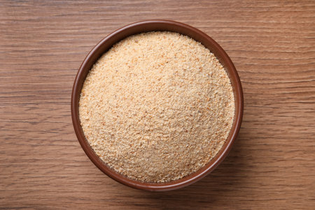 Fresh bread crumbs in bowl on wooden table, top viewの写真素材