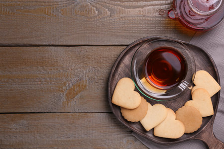 Heart shaped cookies with tea served on wooden table, flat lay. Space for textの写真素材