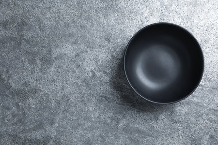 Empty clean ceramic bowl on gray table, top view. Space for textの写真素材