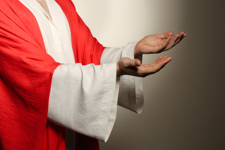 Jesus Christ reaching out his hands on beige background, closeupの写真素材