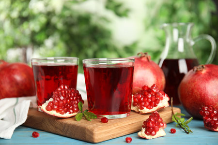 Pomegranate juice and fresh fruits on light blue wooden table outdoorsの写真素材