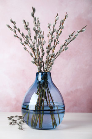 Beautiful bouquet of pussy willow branches in vase on white wooden tableの写真素材